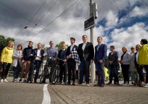 Cilvēki stāv ielas malā